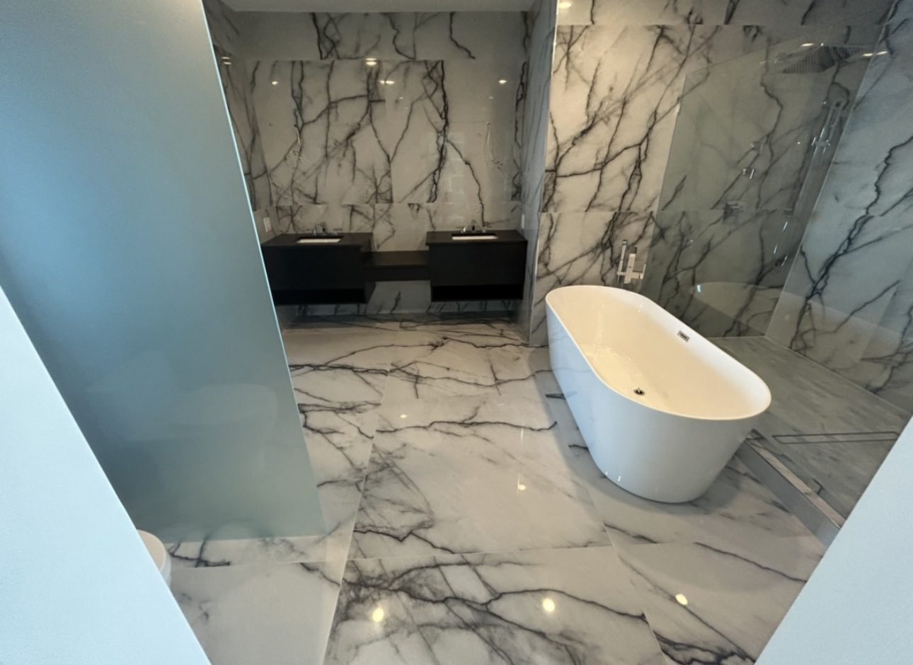 Primary bathroom remodel with book-matched marble walls, freestanding soaking tub and dual vanity, Oakland County Michigan