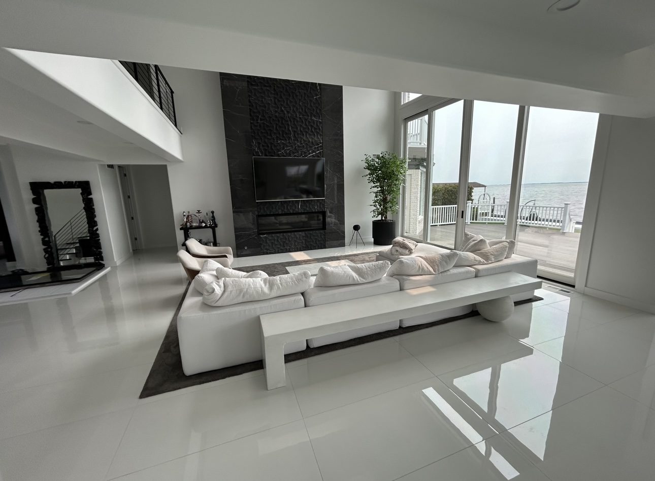 Renovated waterfront living room with black marble fireplace wall, by Mount Vernon Construction Co.