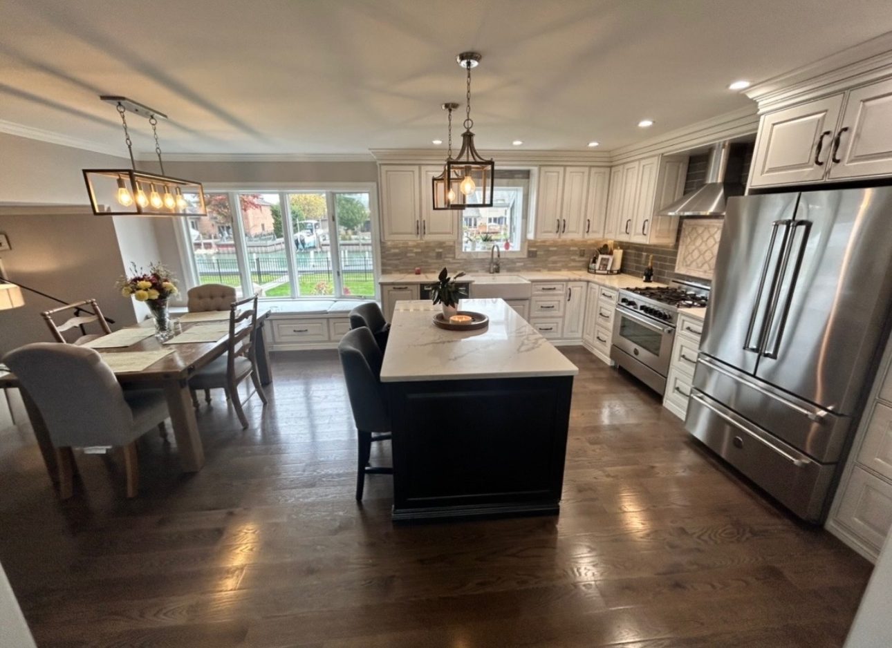 Remodeled kitchen with cream custom cabinetry, dark quartz-topped island, stone backsplash and hardwood floors, Oakland County Michigan